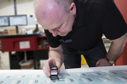 Photo of labels being inspected for quality control by a mem